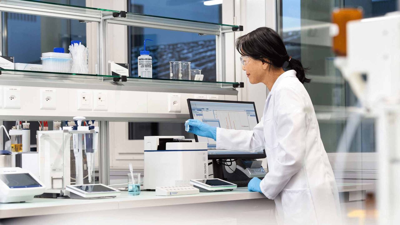 Woman at a lab bench with a UV7 Spectrophotometer with Rainin Pipette